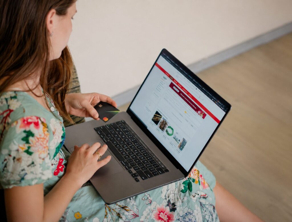 Woman shopping online on a laptop while holding a credit card.