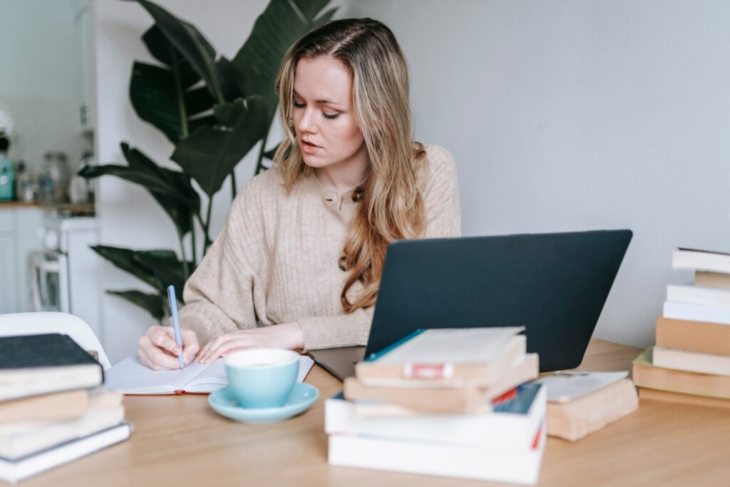 Writer taking notes beside books and a laptop, illustrating how readers evaluate an author's track record.