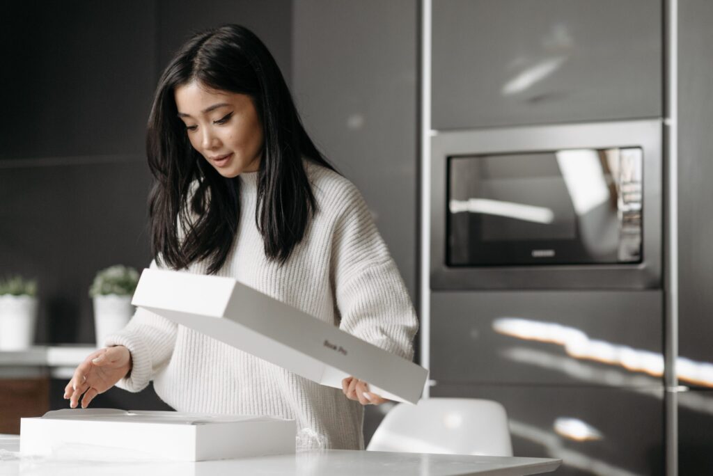 Person comparing new and refurbished electronics before purchasing online.